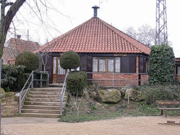 La casa de El Molino de Berola: tejado de teja, paredes de madera y ladrillo y escalera de entrada entre setos