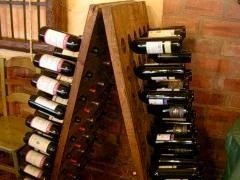 Botellero de madera con vinos junto a la pared de ladrillo